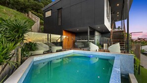 A modern house with a swimming pool, outdoor seating, and a wooden deck. - Luxury Palm Cove Retreat with Pool & Sauna | Sea-renity at Palm Cove (Palm Cove)