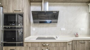Een moderne keuken met een ingebouwde oven, een roestvrijstalen afzuigkap en houten keukenkastjes.
