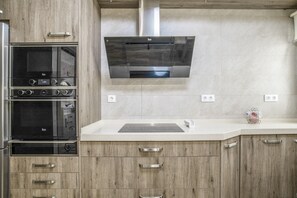 Eine moderne Küche mit Einbauofen, Edelstahl-Dunstabzugshaube und Holzschränken.