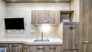 Een moderne keuken met een inbouwspoelbak, houten kastjes en een flatscreen televisie aan de muur.