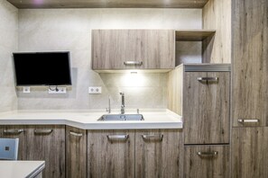 Eine moderne Küche mit integriertem Spülbecken, Holzschränken und einem an der Wand befestigten Flachbildfernseher.