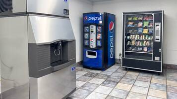 Een professionele keuken met een roestvrijstalen koelkast, een Pepsi automaat en een koelvitrine.