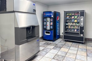 Une cuisine professionnelle équipée d’un réfrigérateur en acier inoxydable, d’un distributeur automatique de boissons Pepsi et d’une vitrine réfrigérée.