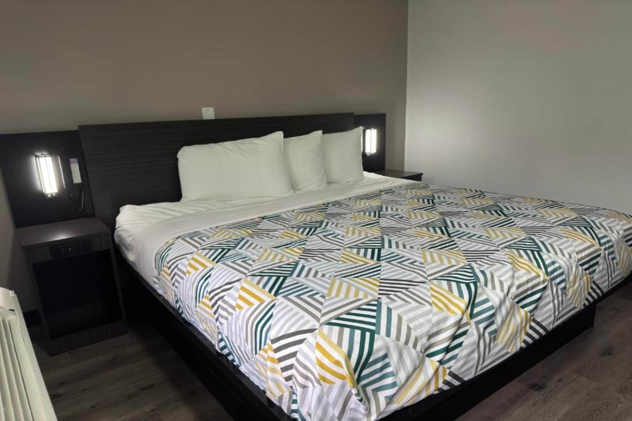 Ein Hotelzimmer mit einem Bett, einem Nachttisch, einer Wandlampe und einer Heizung.