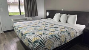Habitación de hotel con cama, ventana con cortinas, aire acondicionado de pared y mesita de noche.