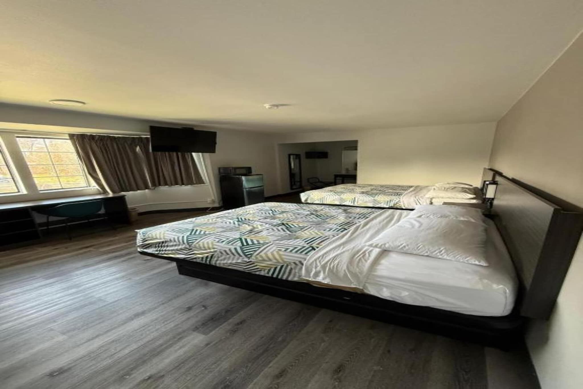 Moderni hotellihuone, jossa on suuri sänky, työpöytä ja ikkuna, jossa on verhot.