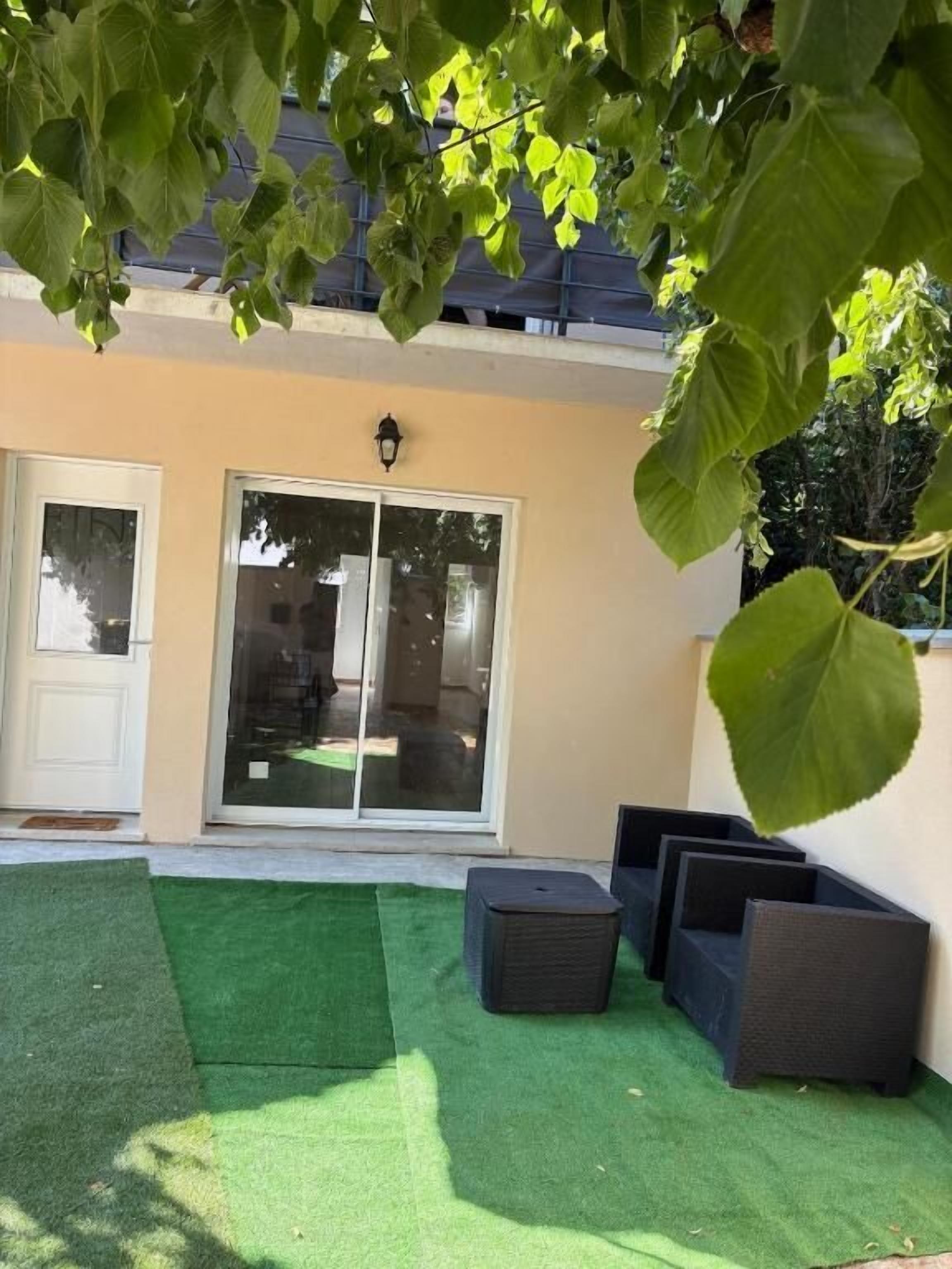 A patio with artificial grass, a sliding glass door, and outdoor furniture.