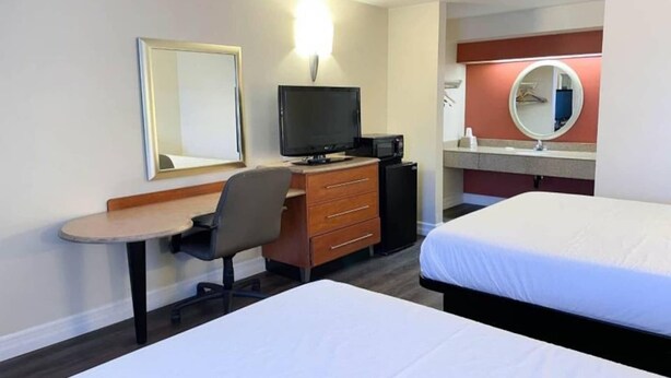 Une chambre d’hôtel comprenant un lit, un bureau avec une chaise, une télévision, une commode et un miroir.