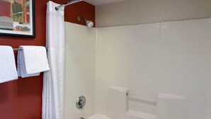 A shower with a glass door, a towel rack with white towels, and a framed picture on the wall.
