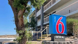 Señal de motel con el número 6 y una flecha que apunta a la derecha, indicando la entrada.