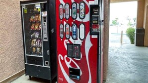 Una máquina expendedora con el logotipo de Coca-Cola, un terminal de pago y una variedad de bocadillos.