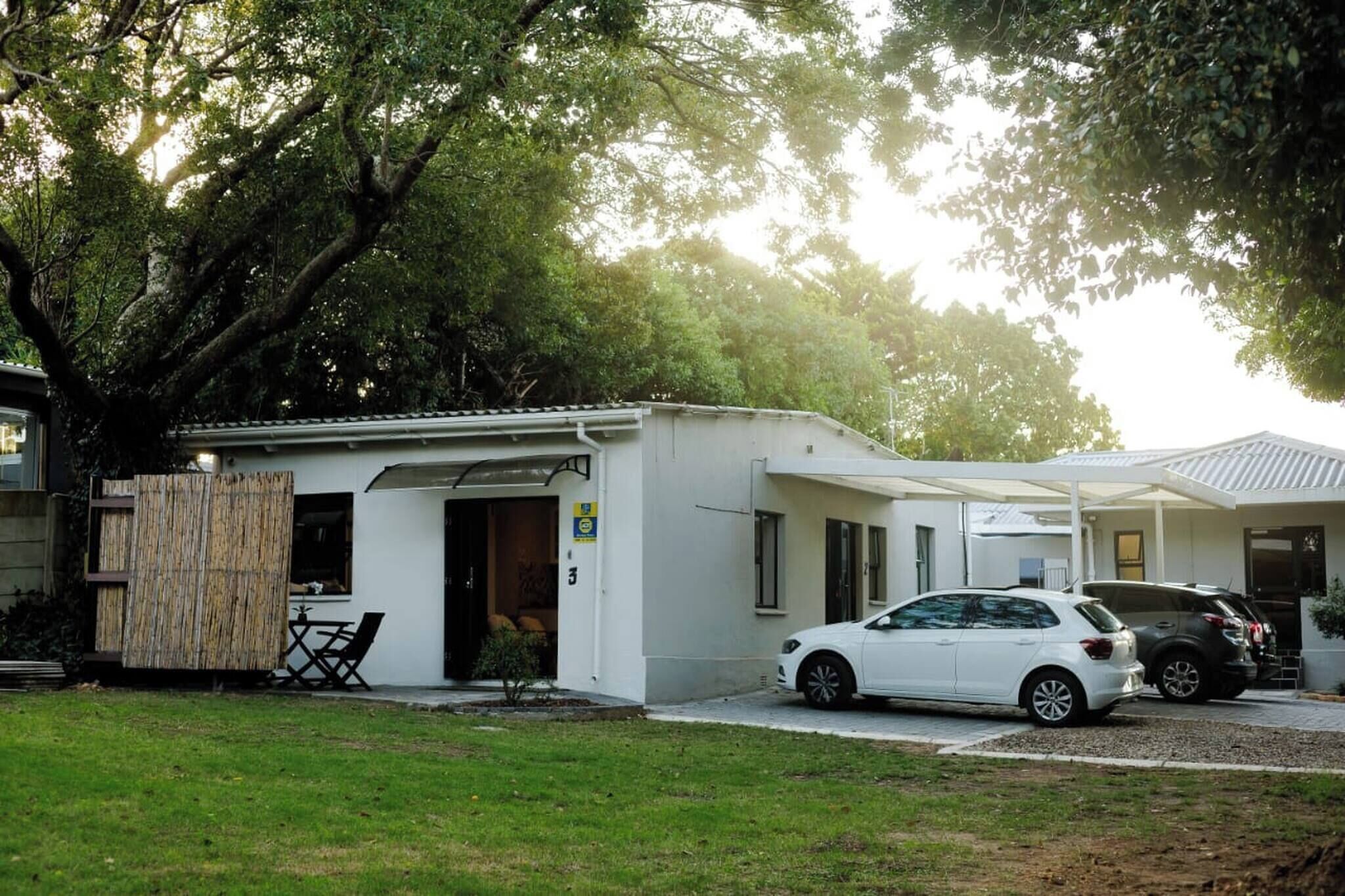 Un petit bâtiment d’un seul étage, doté d’un espace extérieur couvert avec des sièges et d’une voiture garée devant.