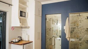 Une salle de bain compacte avec douche, micro-ondes et lavabo.