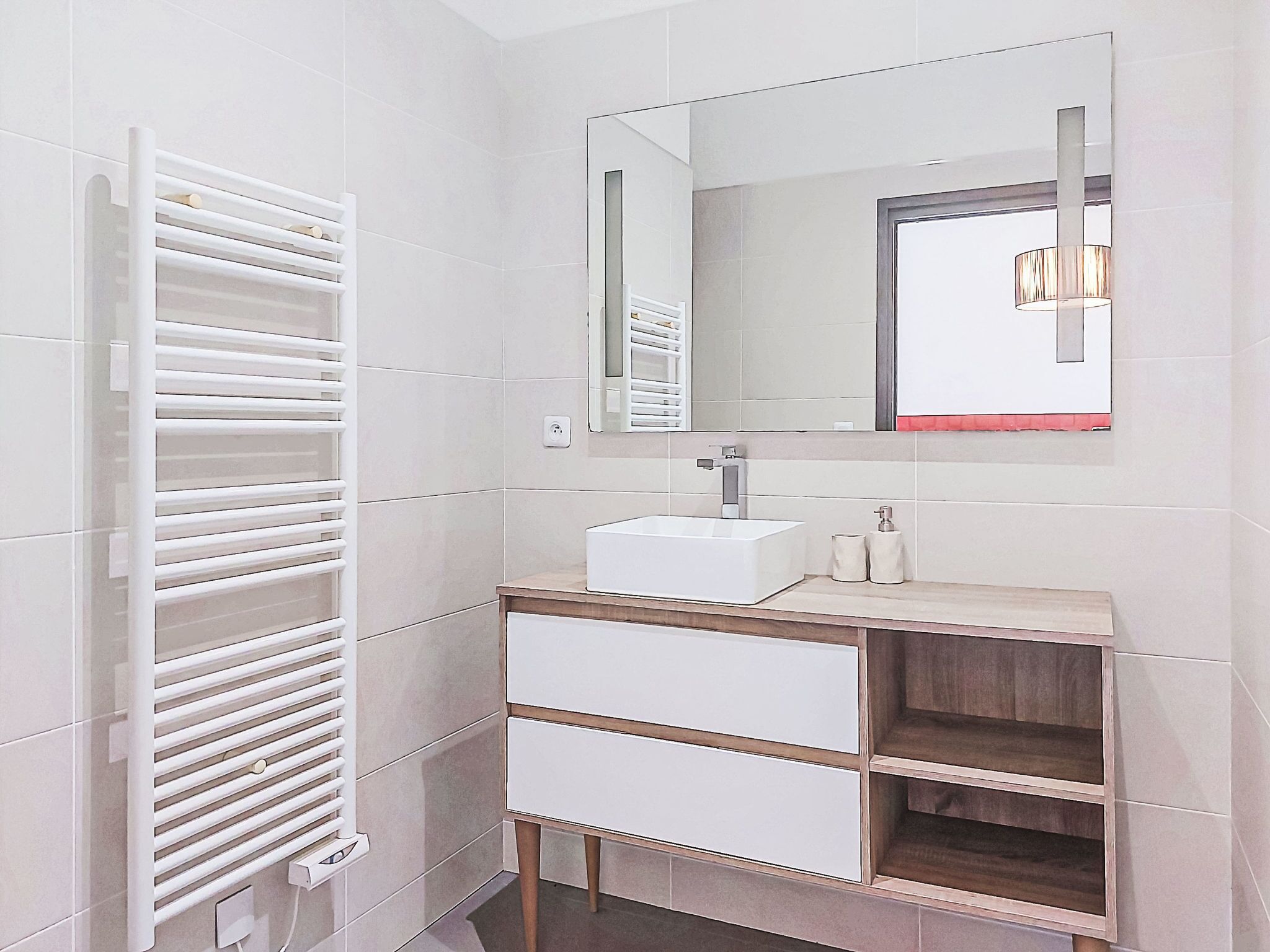A modern bathroom with a white vanity, a rectangular mirror, and a towel rack.