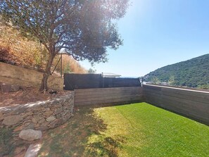 A stone wall, a wooden fence, and a grassy area with a tree. - E Follicie by Interhome (Miomo)