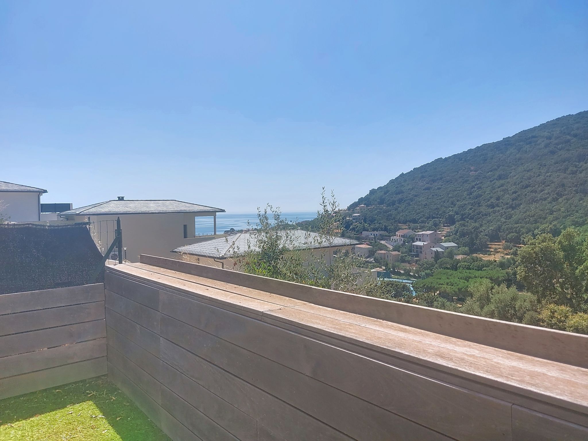 Un balcon avec vue sur une ville côtière et une colline.