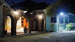 Un arc en pierre mène à un bâtiment doté d’une porte, qui est entouré de plantes en pot et d’un espace bien éclairé.