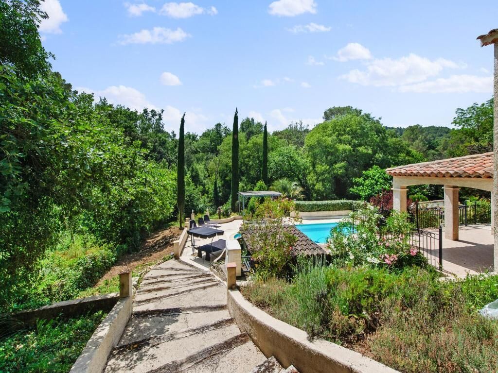 A pathway leading to a pool area with outdoor seating and a gazebo.