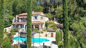 Eine Villa mit Swimmingpool, umgeben von Bäumen und einer Treppe, die zu der oberen Etage führt.