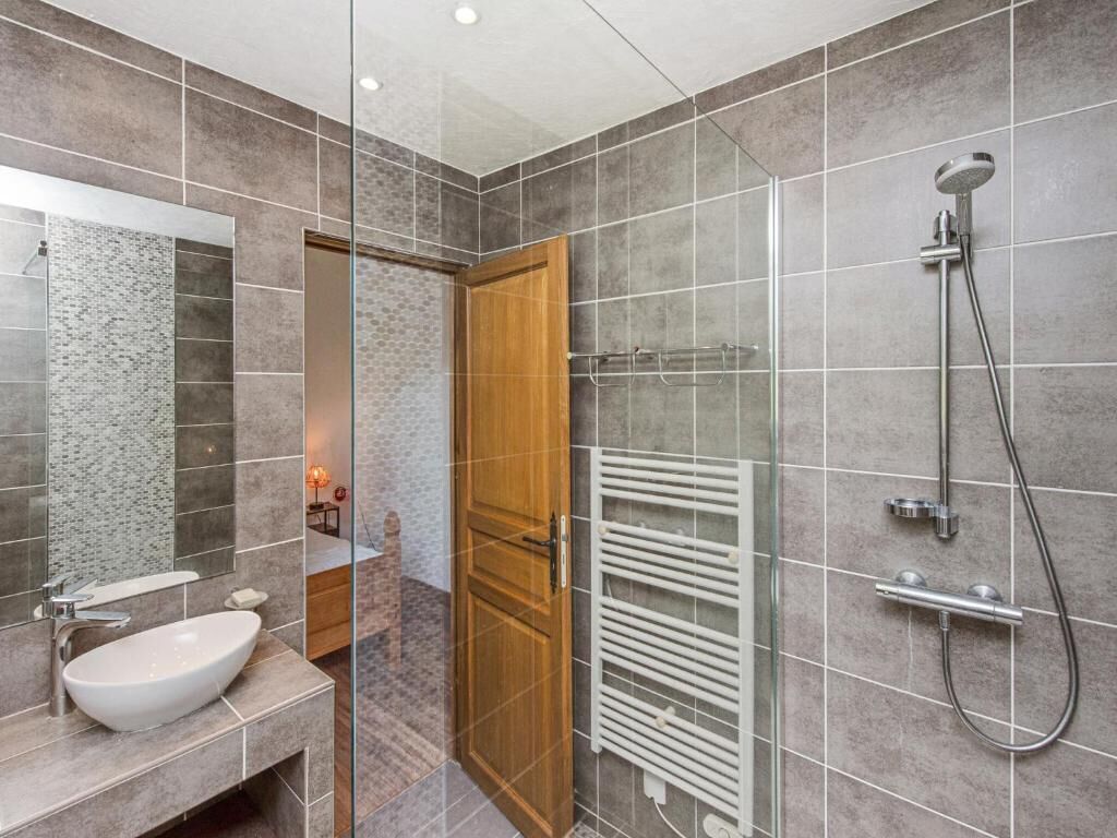 Een moderne badkamer met een glazen douchecabine, een ingebouwd wastafelmeubel en een handdoekrek.