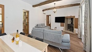 Ein modernes Wohnzimmer mit einer Couch, einem Esstisch und einem Fernseher.
