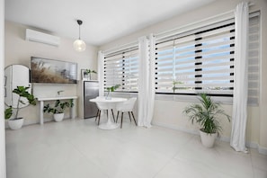 A modern kitchen with a dining area, white cabinetry, a flat-screen TV, and potted plants. - Naya Sanctuary - Brisas (San Juan city)