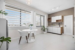 A modern kitchen with white cabinets, a wooden countertop, and a window with blinds. - Naya Sanctuary - Brisas (San Juan city)