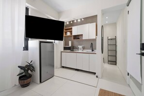 A modern kitchen with white cabinets, a built-in microwave, and a refrigerator. - Naya Sanctuary - Zenn (San Juan city)