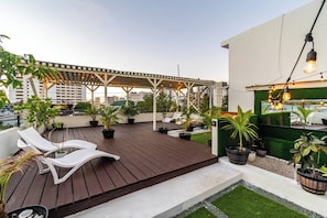 Eine Dachterrasse mit einer Pergola, Liegestühlen, Pflanzkübeln und einem Poolbereich.