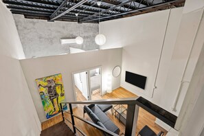 A modern interior with a staircase, a flat-screen TV, and a colorful abstract painting. - Barrio Sanctuary - Bosque Azul (San Juan city)