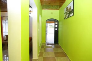 A hallway with a green wall, a door at the end, and a framed picture on the wall.