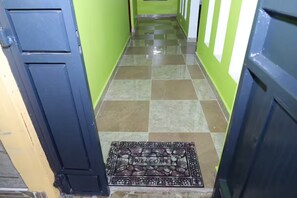 A hallway with a checkered floor pattern, a welcome mat, and a door frame.