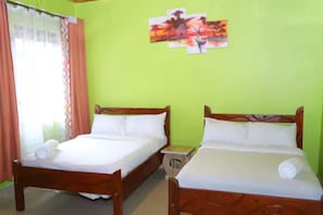 A room with two wooden beds, a small wooden nightstand, and a window with curtains.