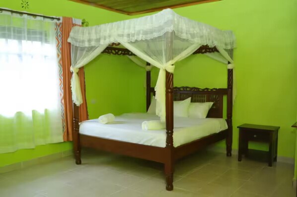 A four-poster bed with a canopy, a bedside table, and a window with curtains.