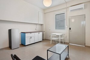 Eine moderne Küche mit einem Kühlschrank, einem blauen Schrank, einem weißen Tisch und einer Glaswand.