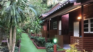 A wooden house with a covered porch, surrounded by a garden with a green pathway. - Grand Tree Resort (Ko Chang)