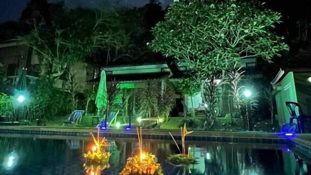 A nighttime pool area with a moon in the sky, a tree, and a building in the background. - Grand Tree Resort (Ko Chang)