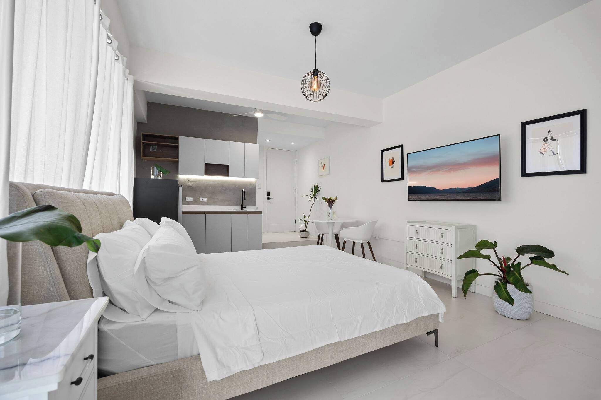 Een moderne slaapkamer met een bed, nachtkastje en uitzicht op de keuken.