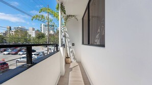 Un balcón estrecho con vista a un estacionamiento y edificios.