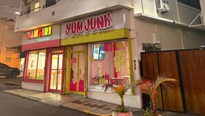 Un edificio de varios pisos con un restaurante llamado 'Yum Junk' en la planta baja.