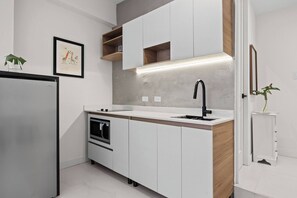 A modern kitchen with white cabinetry, a built-in oven, a black faucet, and a wooden countertop. - Naya Sanctuary - Serena 1 (San Juan city)