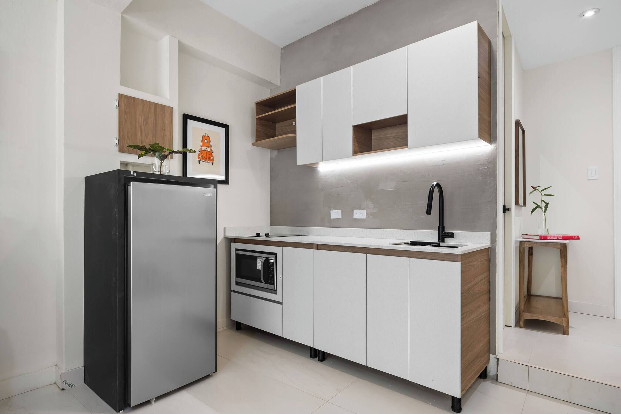 Une cuisine moderne dotée d’un four encastré, d’un réfrigérateur en acier inoxydable et d’un plan de travail en bois.