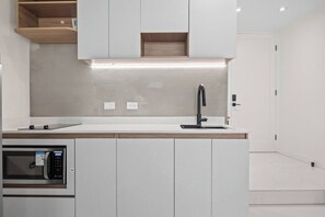 Eine moderne Küche mit integriertem Mikrowellenherd, einem Edelstahlarmaturen und Holzschränken.