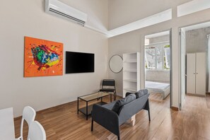 A modern living room with a sofa, a coffee table, a TV, and a colorful abstract painting. - Barrio Sanctuary - Luna (San Juan city)