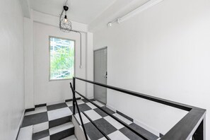Eine Treppe mit schwarz-weiß kariertem Boden, einem Metallgeländer und einem Fenster mit Blick auf Grünflächen.