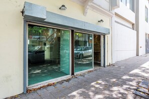 Un bâtiment doté de grandes fenêtres en verre, d’un trottoir pavé et d’une voiture garée devant.