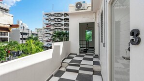 A narrow corridor with a checkered floor, a door with a number, and an air conditioning unit on the wall. - Barrio Sanctuary - Sol (San Juan city)