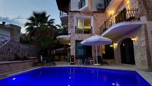Ein Poolbereich mit Pool, Gartenmöbeln und einem Gebäude mit Balkonen.