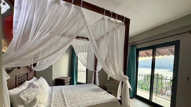 Ein Schlafzimmer mit einem Himmelbett, einem Nachttisch, einem Fenster mit Blick und einem Balkon.