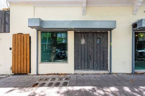 A building facade with a wooden door, a window, and a metal gate. - Barrio Sanctuary - Encanto (San Juan city)